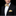 Man wearing a black suit with a yellow patterned bow tie and pocket square on a black background