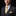 Man wearing a dark suit with a yellow tie and pocket square against a black background