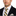 Man wearing a black suit with a white shirt and yellow striped tie on a white background