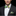 Man wearing a black suit with a colorful bow tie and pocket square on a black background