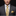 Man wearing a gray suit with a yellow paisley tie and pocket square on a black background