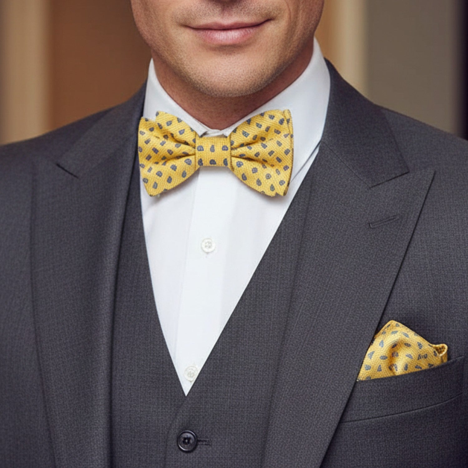 Man wearing a gray suit with a yellow bow tie and pocket square.