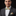 Man wearing a gray suit with a colorful bow tie and pocket square on a black background