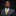 Man wearing a gray suit with a colorful tie and pocket square on a black background