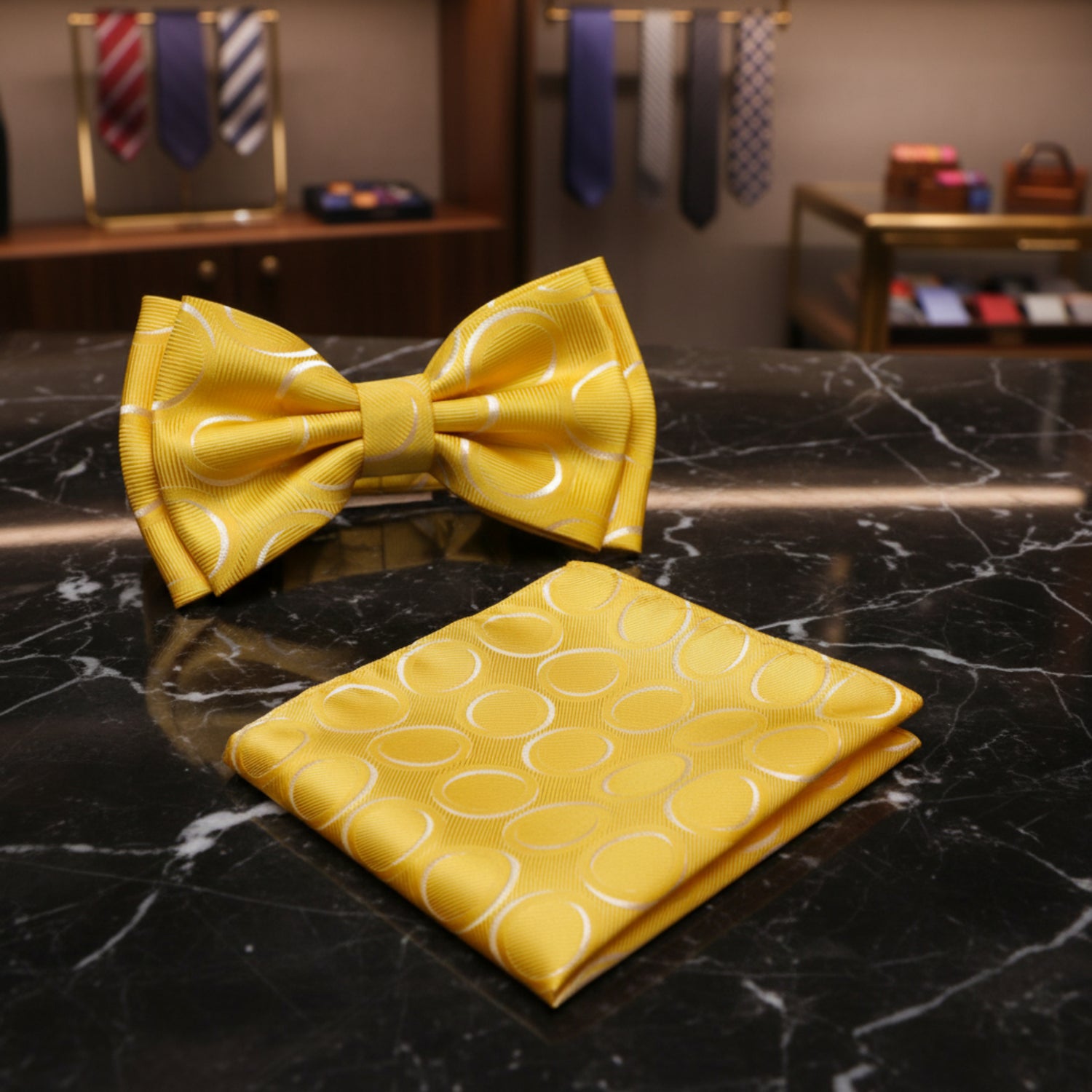 A yellow satin bow tie and matching pocket square set, both featuring a subtle white circular pattern, displayed on a solid white background.