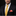 Man wearing a black suit with a yellow tie and red pocket square against a black background