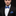 Man wearing a black suit with a blue bow tie and pocket square on a black background
