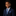Young boy in a navy suit with a blue patterned tie and pocket square on a black background