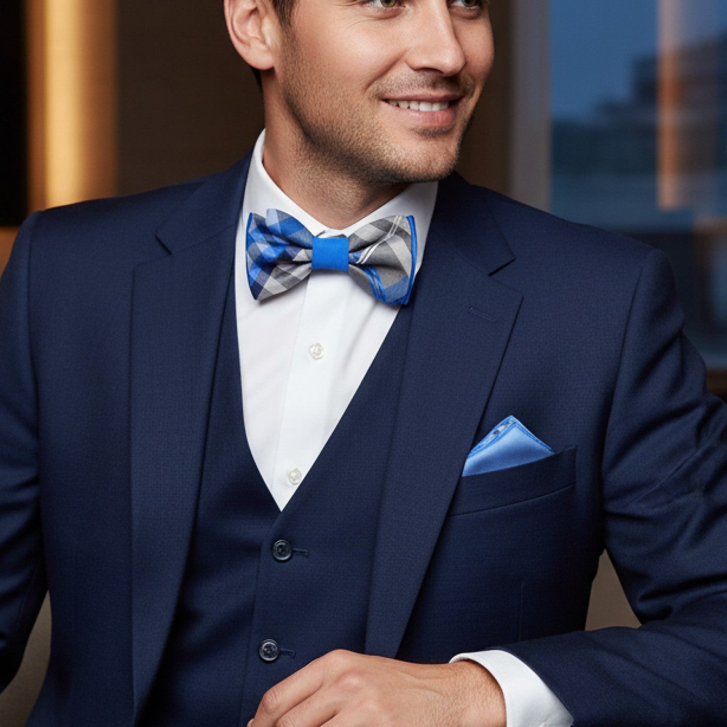 Man wearing a navy suit with a blue bow tie and pocket square.