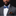 Man wearing a gray suit with a blue bow tie and brown pocket square on a black background