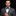 Man wearing a gray suit with a patterned bow tie and pocket square on a black background