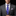 Man wearing a gray suit with a purple plaid tie and white shirt against a black background