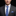 Man wearing a gray suit with a blue tie and pocket square on a black background