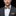 Man wearing a gray suit with a gold bow tie and pocket square on a black background