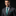 Man wearing a gray suit with a green tie and pocket square on a black background