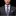 Man wearing a gray suit with a colorful tie and pocket square on a black background