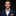 Man wearing a navy suit with a beige bow tie and pocket square on a black background
