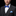 Man wearing a black suit with a blue plaid bow tie and light blue pocket square on a black background