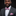 Man wearing a gray suit with a pink bow tie and pocket square on a black background