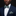 Man wearing a navy suit with a green bow tie and pocket square against a black background