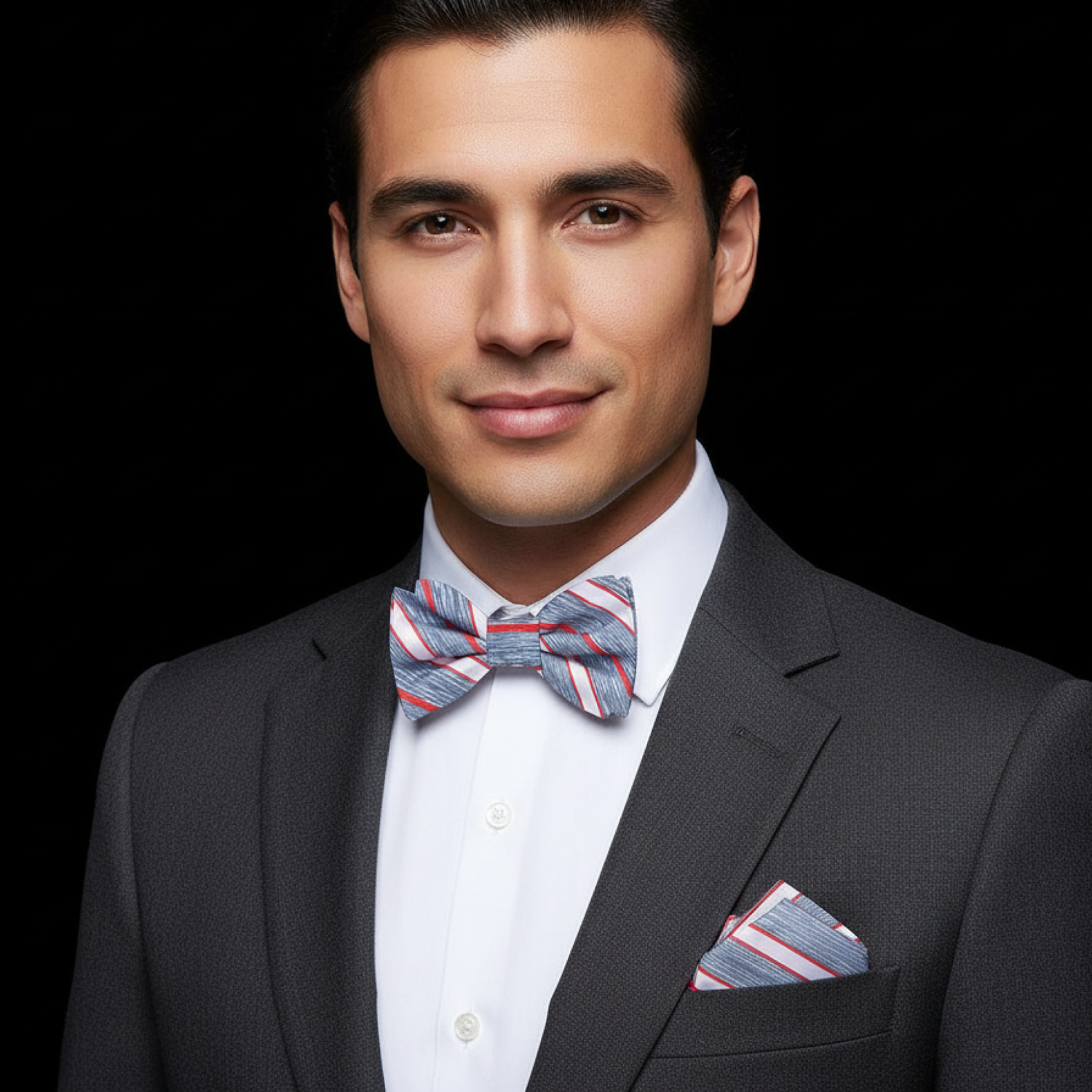 Man wearing a suit with a striped bow tie and pocket square on a black background