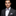 Man wearing a suit with a striped bow tie and pocket square on a black background