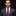 Man wearing a gray suit with a red paisley tie and pocket square on a black background