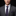 Man wearing a gray suit with a purple tie and pocket square on a black background
