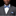 Man wearing a gray suit with a blue and white striped bow tie and pocket square on a black background