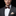 Man wearing a gray suit with a brown bow tie and accenting cream floral pocket square on a black background