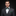 Man wearing a gray suit with a green bow tie and pocket square on a black background