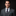 Man wearing a gray suit with a colorful tie and pocket square on a black background