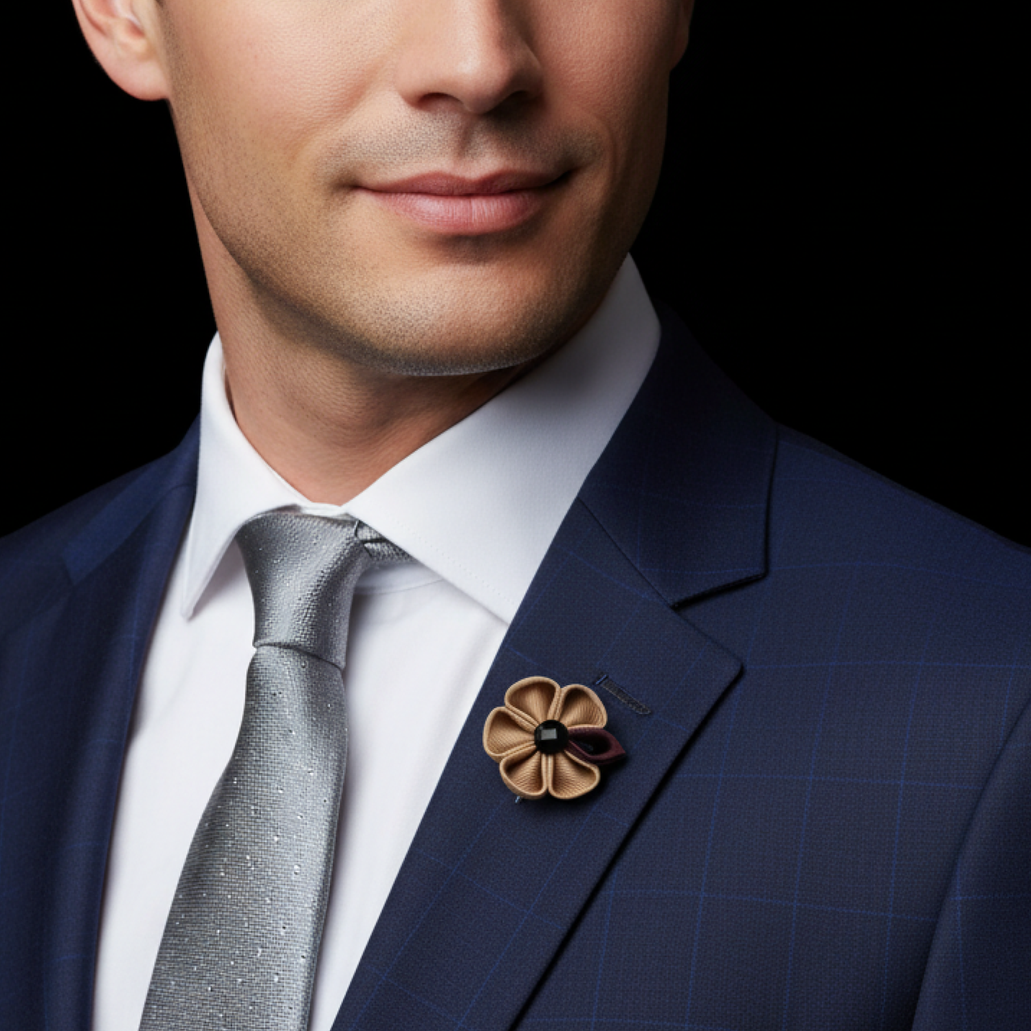 Man wearing a navy suit with a gray tie and floral lapel pin on a black background
