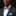 Man wearing a black suit with a colorful bow tie and blue pocket square on a dark background