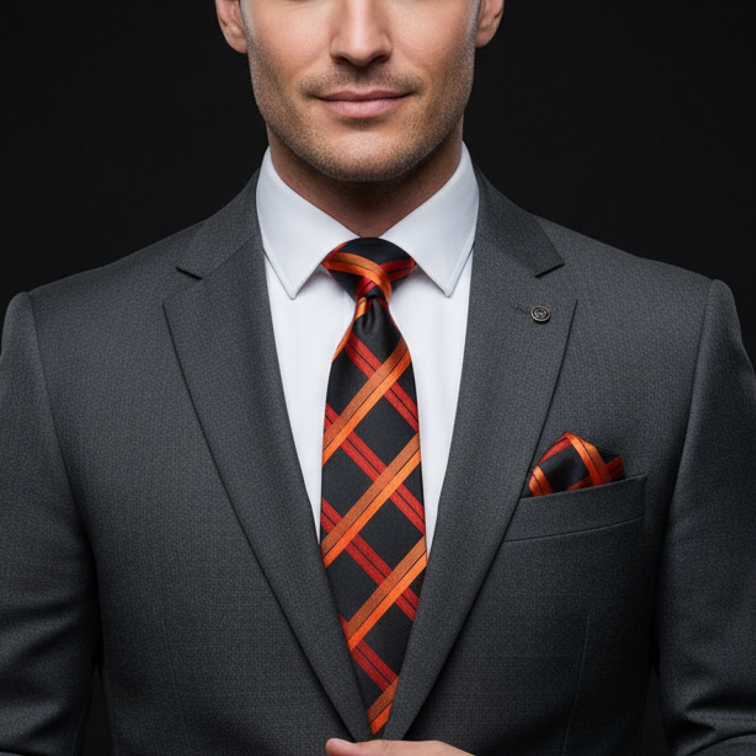 Man wearing a gray suit with an orange and black tie against a black background