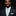 Man wearing a dark suit with a light green tie against a black background