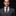 Man wearing a gray suit with a patterned tie and pocket square on a black background