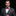 Man wearing a gray suit with a red bow tie and pocket square on a black background