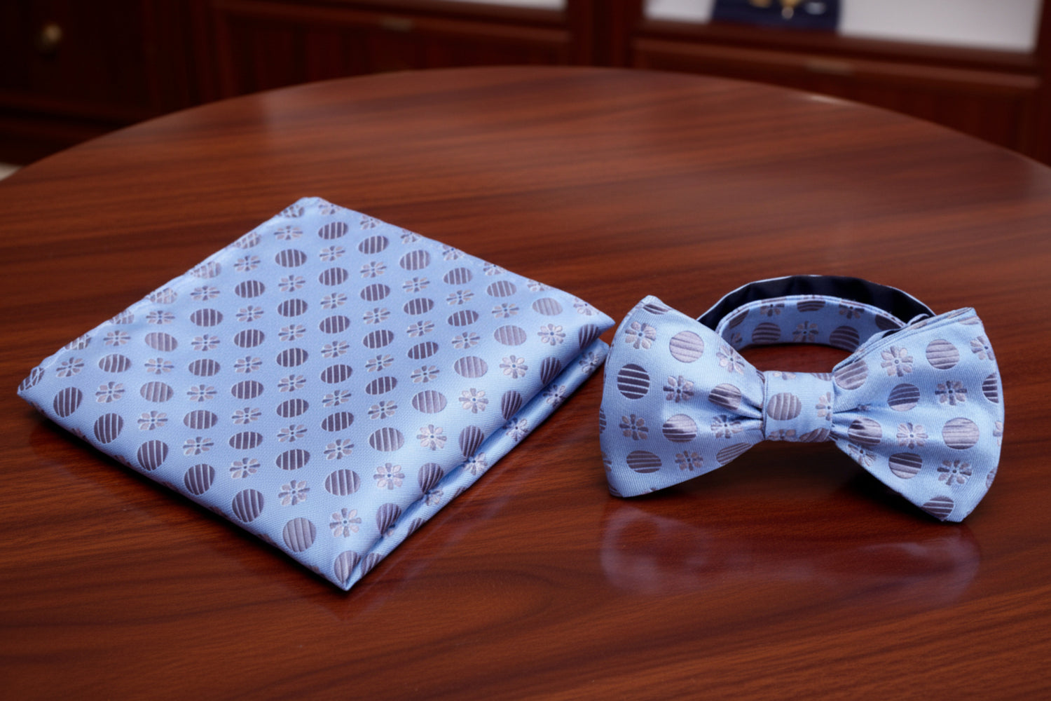 Blue patterned bow tie and pocket square set on a mahogany background