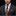 Man wearing a dark suit with a patterned tie and pocket square against a black background
