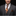 Man wearing a gray suit with a patterned tie and pocket square on a black background