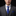 Man wearing a gray suit with a blue tie and pocket square on a black background