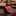 A rolled red necktie with vertical stripes featuring a small white and dark pattern, 