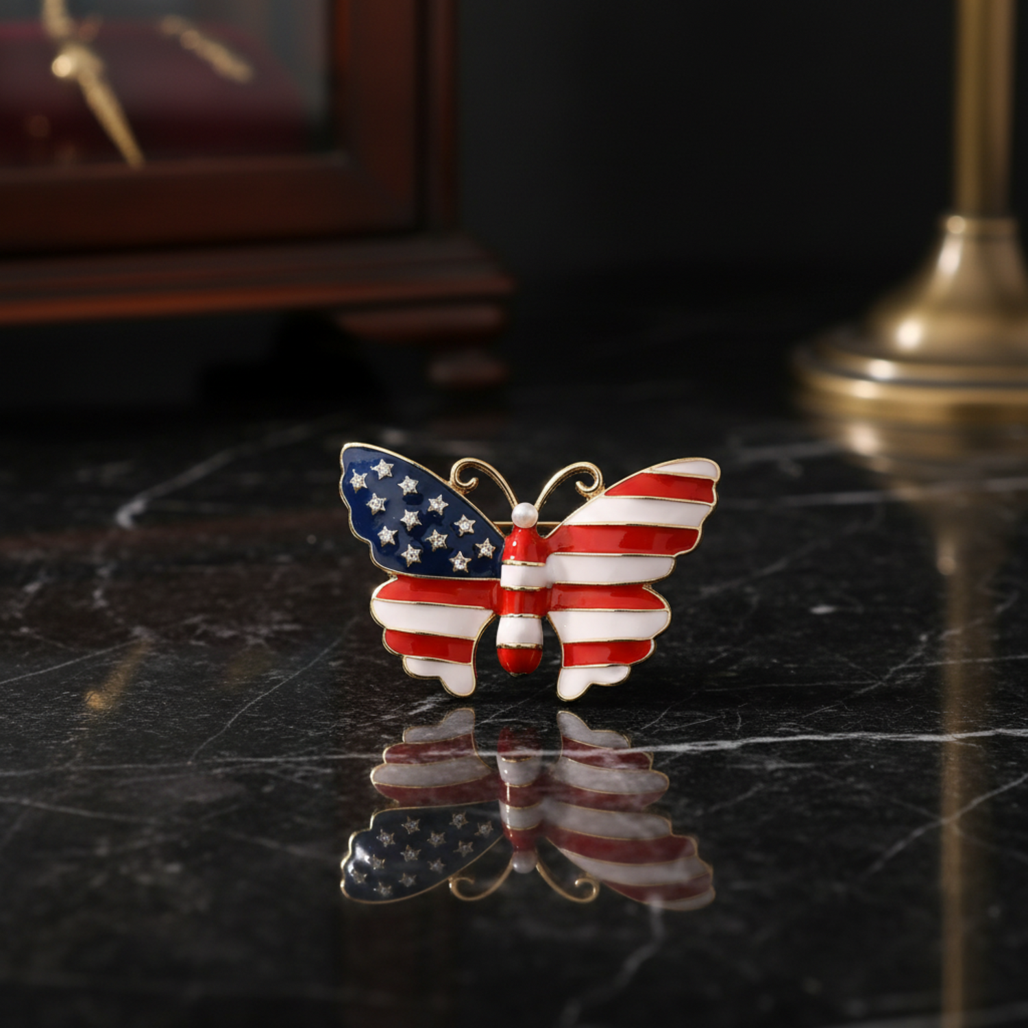 A butterfly-shaped enamel pin featuring an American flag design with red and white stripes and a blue wing with white stars, outlined in gold metal