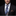 Man wearing a black suit with a patterned blue tie and brown pocket square on a dark background