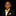 A young boy wearing a black suit jacket, white dress shirt, and a bright yellow patterned bow tie and pocket square, photographed against a solid black background.