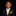 A young boy wearing a black suit, white dress shirt, and a bright yellow striped tie with a matching yellow pocket square, set against a solid black background.