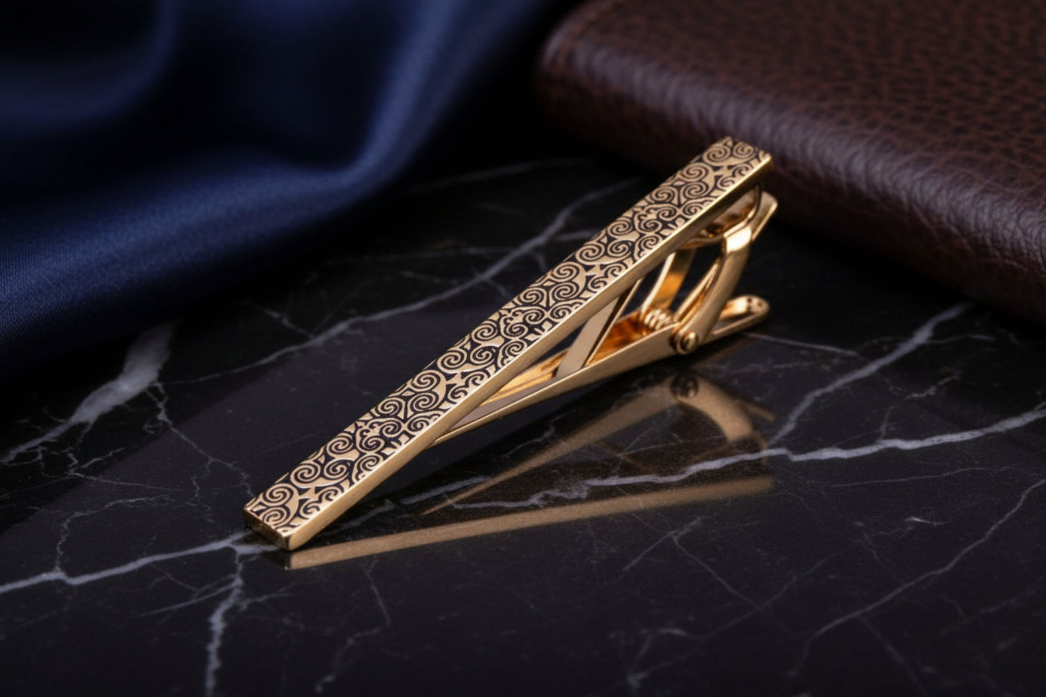 A gold colored intricate vine design tie bar