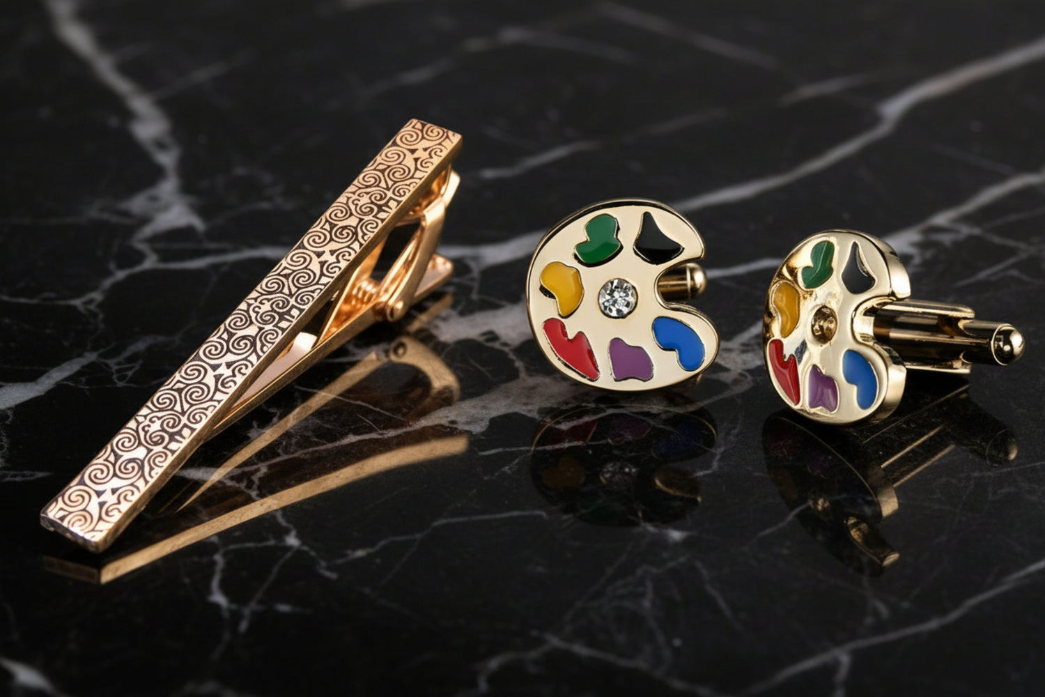 A gold colored intricate vine design tie bar with artist color palette design cuff-links set