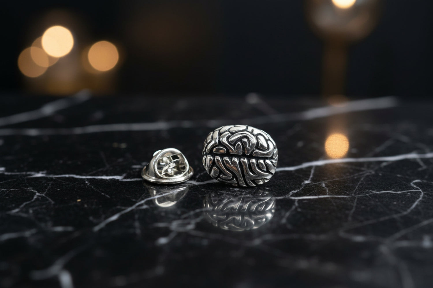 A chrome colored brain shaped lapel pin